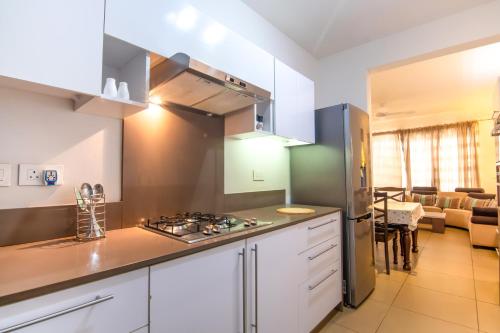 een keuken met witte kasten en een fornuis met oven bij Two Bedroom Apartment with Garden and Pool Access - Azuri Village, Roches Noires in Roches Noires