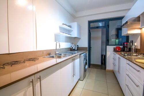 a kitchen with white cabinets and a sink at Azuri Ocean Village - Elegant 3-Bedroom Apartment with Private Garden, Beach & Pool Access in Roches Noires in Roches Noires