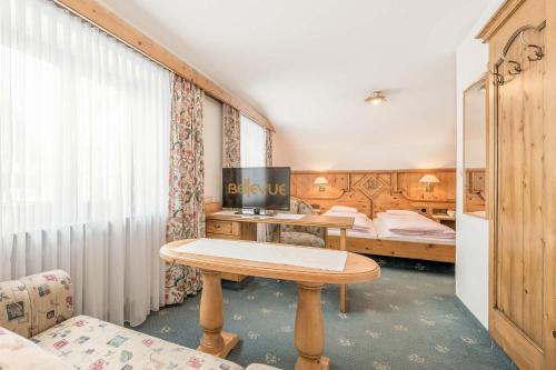 a room with a table and two beds at Hotel Bellevue - 4 Sterne superior in Obergurgl