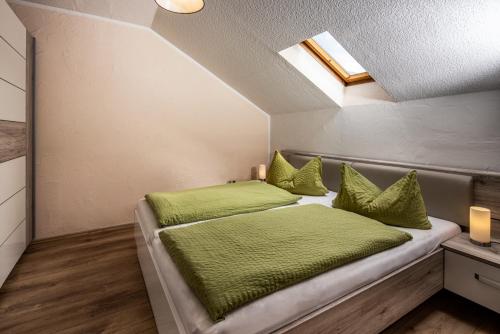 a bedroom with a bed with green sheets and a skylight at Graznhof Pension und Ferienwohnungen in Anger