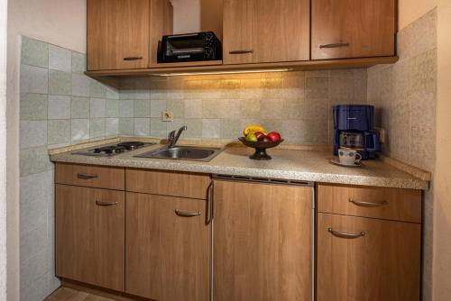 a kitchen with wooden cabinets and a sink with a bowl of fruit at Graznhof Pension und Ferienwohnungen in Anger