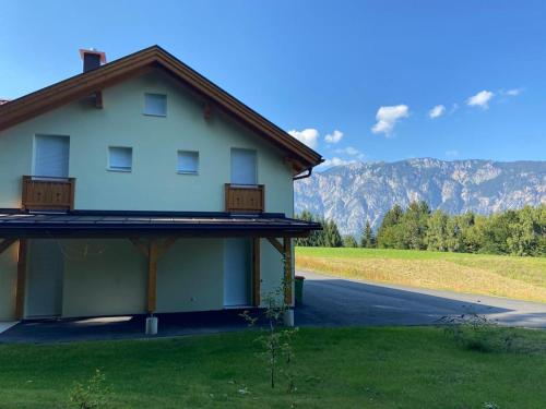 a house on the side of a road with mountains in the background at Oachkatzlschwoaf in Arnoldstein