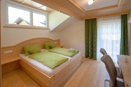 ein Schlafzimmer mit einem Bett mit grünen Kissen und einem Fenster in der Unterkunft Zirbenchalet Grossglockner in Heiligenblut