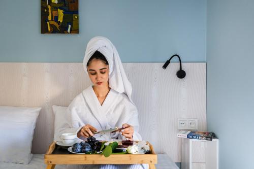 a woman in a bathrobe with a tray of food at Khujra Studios in Bukhara