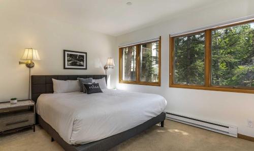 a bedroom with a large bed with two windows at Townsend Place A107 Condo in Beaver Creek