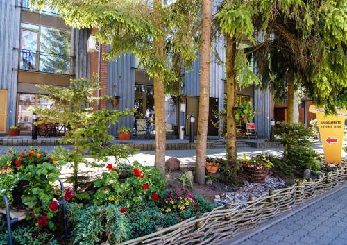 a garden in front of a building with trees and flowers at Saulės Krantas in Palanga