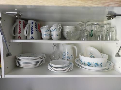 a white cabinet filled with plates and cups and dishes at L'éléphant Blanc de ConcarnOLoc in Concarneau
