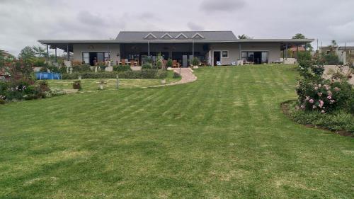 a house with a large lawn in front of it at Goggas Nest BNB & Restaurant in Matsapha