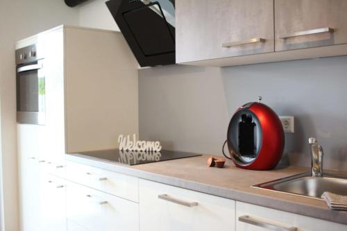 uma cozinha com um lavatório e um aparelho vermelho num balcão em Ferienwohnung Morgensonne em Kenzingen