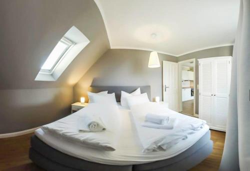 a bedroom with a large white bed with a skylight at FerienDüne 7 in Kägsdorf