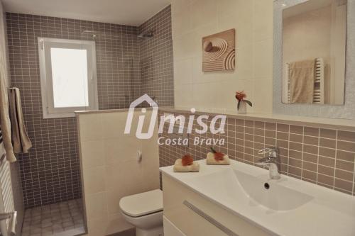 een badkamer met een wastafel, een toilet en een spiegel bij Villa Caraibes in Calonge