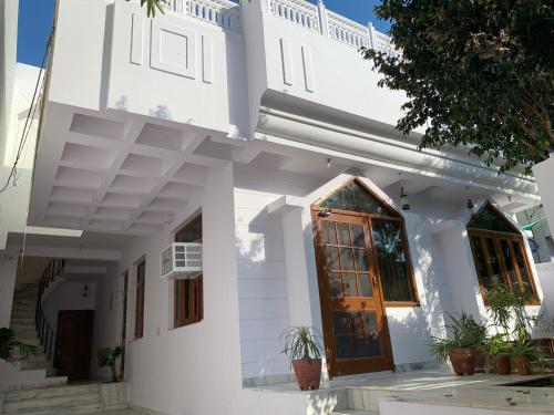 a white house with a wooden door and some plants at The Karauli Villa by Le Pension Stays in Jaipur