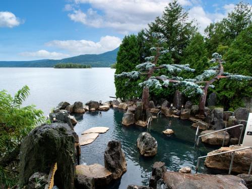 a pool of water with rocks in the middle of a lake at Akan Yuku no Sato Tsuruga in Akankohan