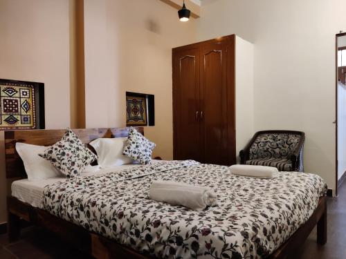 a bedroom with a bed with two pillows and a chair at The Karauli Villa by Le Pension Stays in Jaipur
