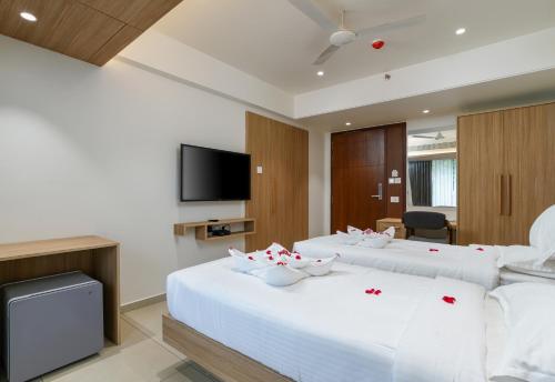a hotel room with two beds and a flat screen tv at The Trios Hotel in Cochin