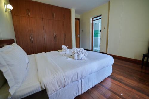ナイロビにあるBatians Apartment Hotelの木製のヘッドボードが付いた白いベッドのある寝室