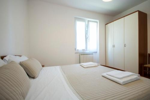 una camera da letto con un grande letto bianco con due asciugamani di Ferienwohnung mit pool am Comer See a Domaso