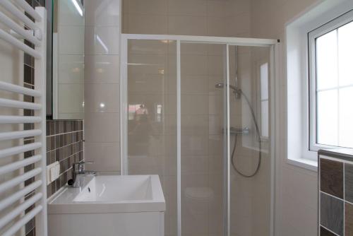 baño blanco con ducha y lavamanos en Chalet bis 5 Personen ohne Hund - a17100, en Flüthörn