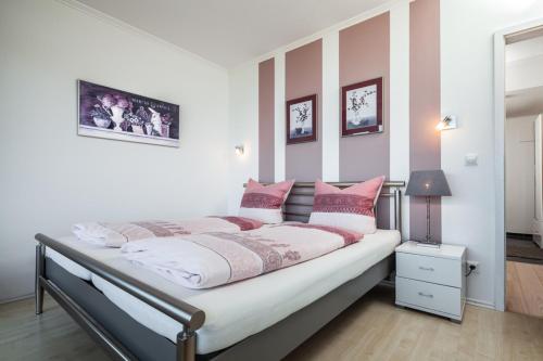 トラフェミュンデにあるFerienwohnung Alastor Travemündeのベッドルーム1室(ピンクと白の枕が備わるベッド1台付)