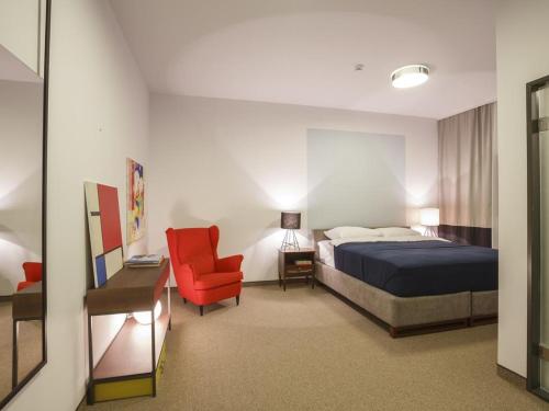 um quarto de hotel com uma cama e uma cadeira vermelha em Savamala b&b em Belgrado
