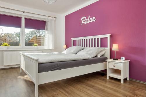 a bedroom with a white bed with a purple wall at Mia in Dahme