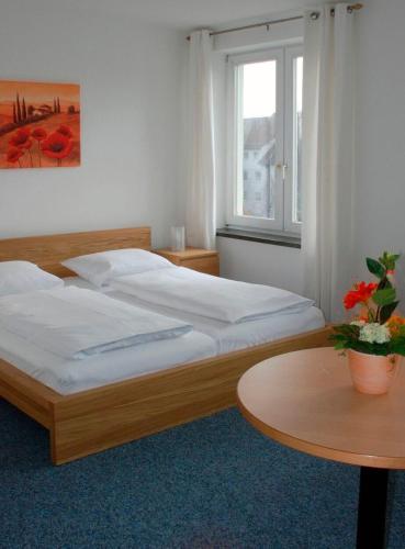een slaapkamer met 2 bedden, een tafel en een raam bij Klein aber fein zentrale Ferienwohnung 30qm im Hotel zur Börse in Hameln