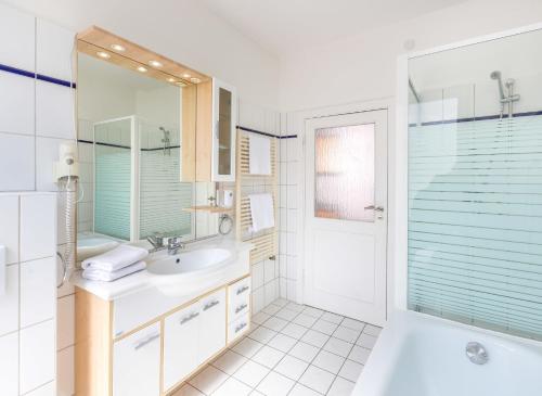 een badkamer met een bad, een wastafel en een douche bij Klein aber fein zentrale Ferienwohnung 30qm im Hotel zur Börse in Hameln