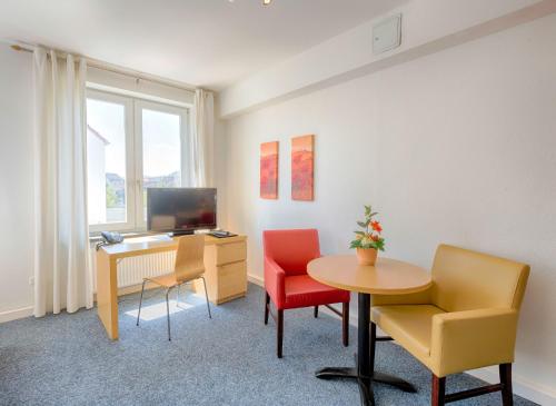 ハーメルンにあるKlein aber fein zentrale Ferienwohnung 30qm im Hotel zur Börseのデスク、椅子2脚、テーブルが備わる客室です。