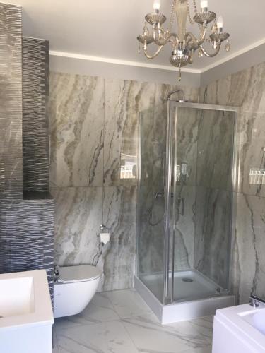 a bathroom with a shower and a sink and a chandelier at Dolcevita Podlasie in Bondary