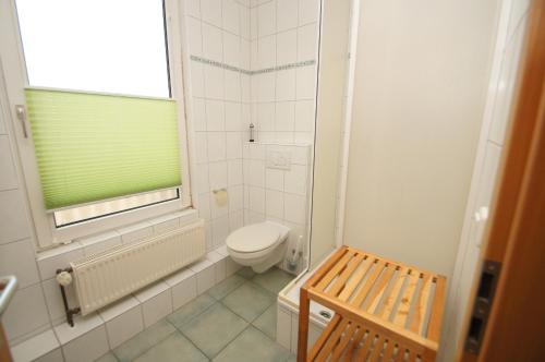 a white bathroom with a toilet and a window at Treibholz in Kellenhusen