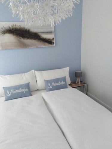 a bedroom with a white bed with pillows and a chandelier at Meerchenhaus "Lagune" in Grömitz