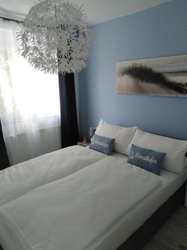 een slaapkamer met een groot wit bed en een kroonluchter bij Meerchenhaus "Lagune" in Grömitz