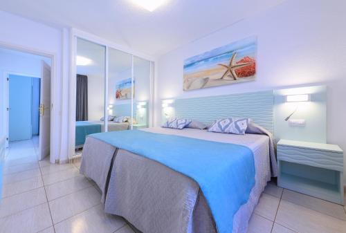 een slaapkamer met een groot bed en een blauwe deken bij Valle Marina Apartamentos in Mogán