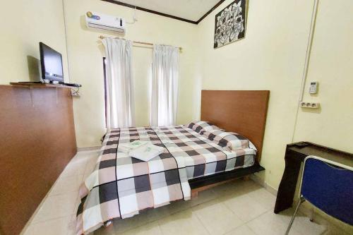 a bedroom with a bed and a television in it at Quattrick Dee Homestay Mitra RedDoorz in Manokwari