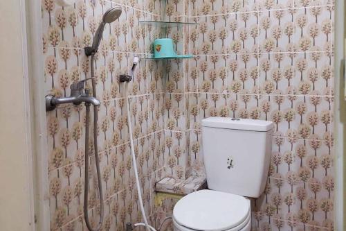 ein Bad mit einem WC und einer Dusche in der Unterkunft Quattrick Dee Homestay Mitra RedDoorz in Manokwari