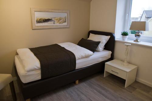sypialnia z łóżkiem z czarnym zagłówkiem i oknem w obiekcie Sunrise w mieście Grömitz