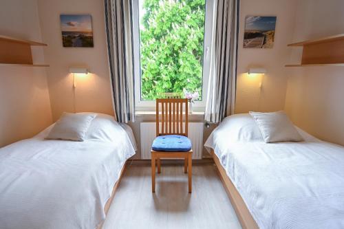 a room with two beds with a chair and a window at Zur schönen Aussicht - FW 9 in Dahme