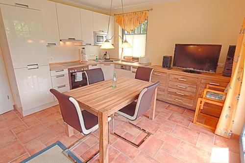 a kitchen with a wooden table and chairs and a television at Villa Birkenboom, FW 1 in Zingst