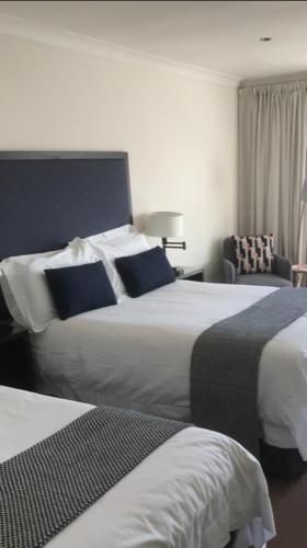 a hotel room with two beds and a chair at Aaron Glen Apartments in Edinburgh