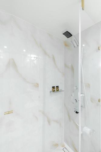 a white bathroom with a shower with a glass door at GRANDE CASTELLANO in Nafplio