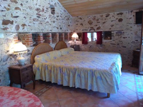 1 dormitorio con 1 cama en una habitación con paredes de piedra en Le POULAILLER, en Mareuil-sur-Lay