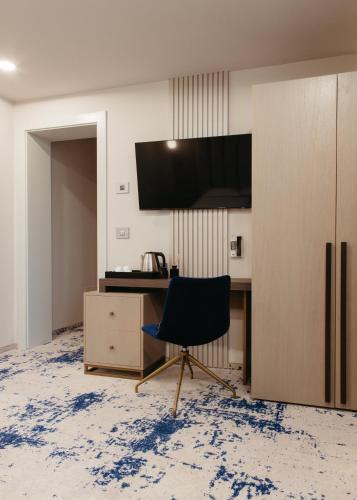 a chair in a room with a desk and a tv at Pensiunea Iristar in Fălticeni