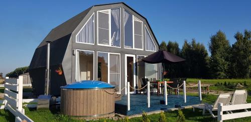 a large black and white house with a table and an umbrella at Saulėlydis in Dreverna