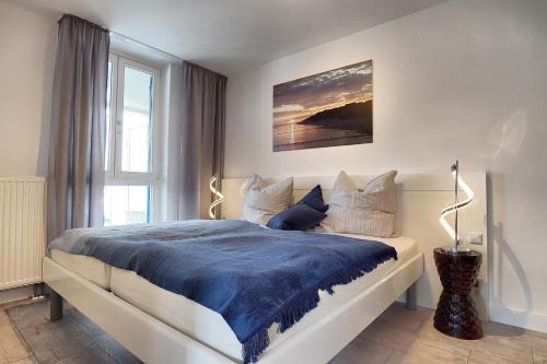 ツィングストにあるAparthotel "Am Kurhaus" 108, App Ostseeblickのベッドルーム1室(大型ベッド1台、青い毛布付)