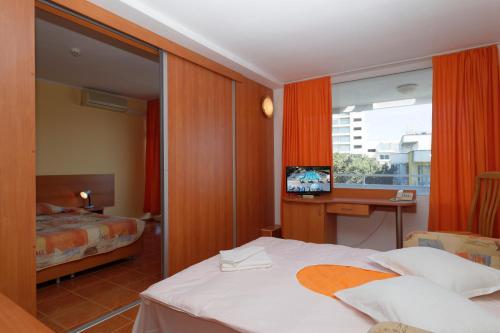 a hotel room with a bed and a desk with a television at Hotel Pliska All inclusive in Golden Sands