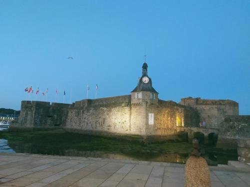 a castle with a clock tower on top of it at L'éléphant Blanc de ConcarnOLoc in Concarneau