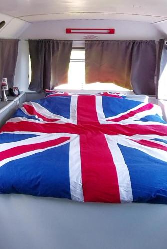 - un lit rouge blanc et bleu dans un van dans l'établissement insolite bus anglais le Buckinghambus, à Saint-Philbert-sur-Risle