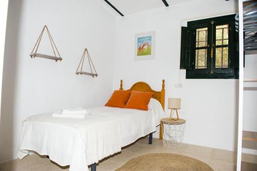 a white bedroom with a bed with orange pillows at Casa Abanto in Ronda