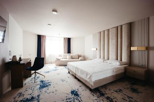 a bedroom with a bed and a desk and a couch at Pensiunea Iristar in Fălticeni