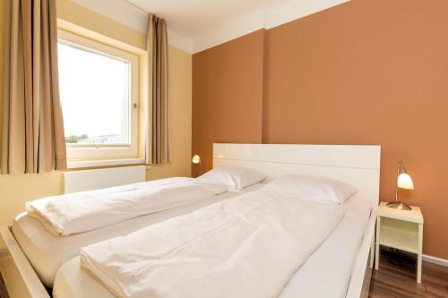 two white beds in a bedroom with a window at ancora Marina Haus 1 Nr 09, Typ 3 in Neustadt in Holstein